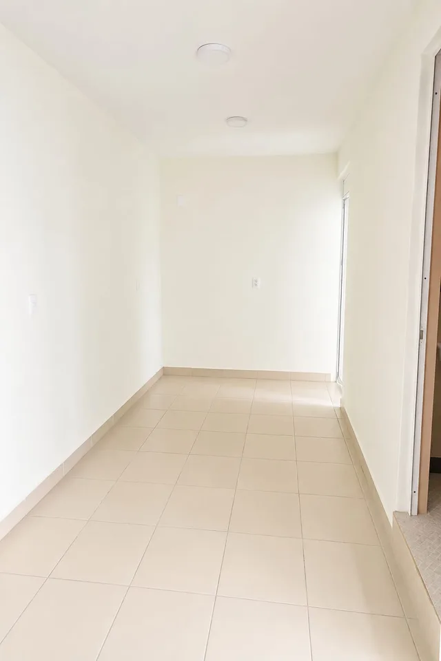 Interior del departamento de doble habitación de LUMA, con paredes blancas y piso de loseta